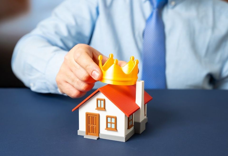 mano con modellino casa e corona